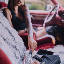 Load image into Gallery viewer, Woman reaches for Voodoo Oil in a car